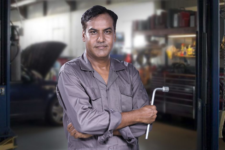 Friendly auto mechanic standing next to tire storage racks