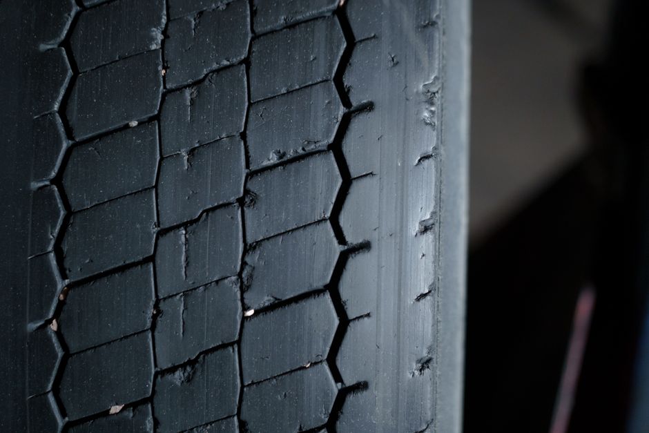 Mechanic checking tire tread and wheel alignment